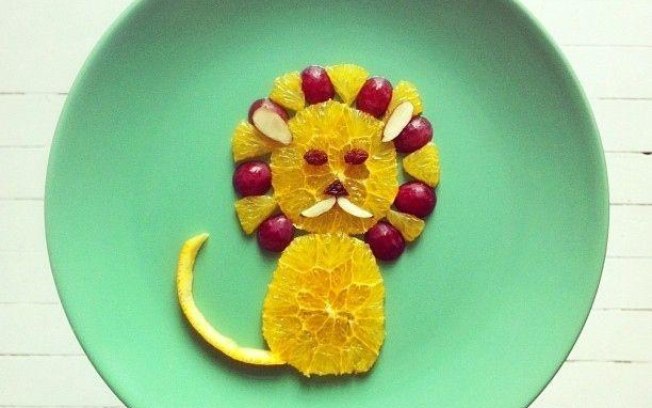 Leão feito com fatias de laranja, uvas e detalhes em amêndoas 