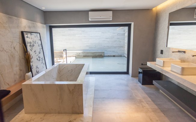 O espaço monocromático de 325 m² integra living, quarto, banheiro, cozinha e área externa com espelho d’água