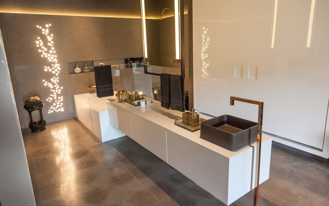 Integrado ao quarto projetado por Toninho Noronha e Renato Andrade, o banheiro ganhou iluminação inusitada com o recorte do porcelanato da parede com efeito de bolhas d'água