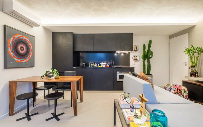 A cozinha americana completamente integrada à sala aumenta o espaço social de um apartamento pequeno